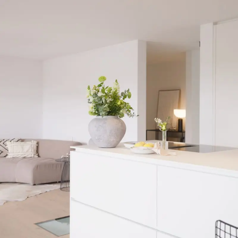 Modernes Wohnzimmer mit einer hellen Kücheninsel, stilvollen Dekorationen und einer gemütlichen Sitzecke.
