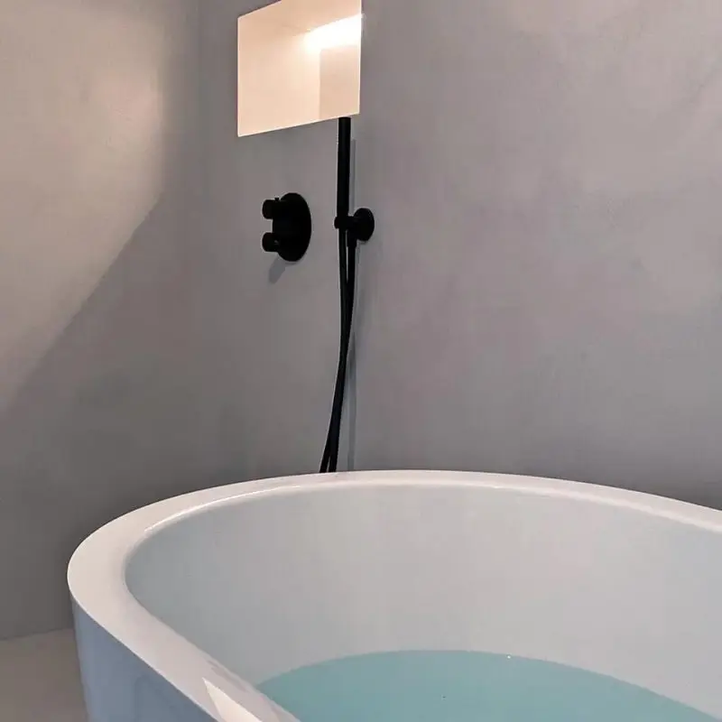 Freistehende Badewanne im Badezimmer des GERBERHAUS6 mit moderner Wandarmatur und fugenlosem Microzement.
