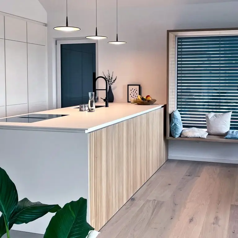 Küche mit großer Kücheninsel und Sitzfenster, flankiert von drei Hängeleuchten im GERBERHAUS7.