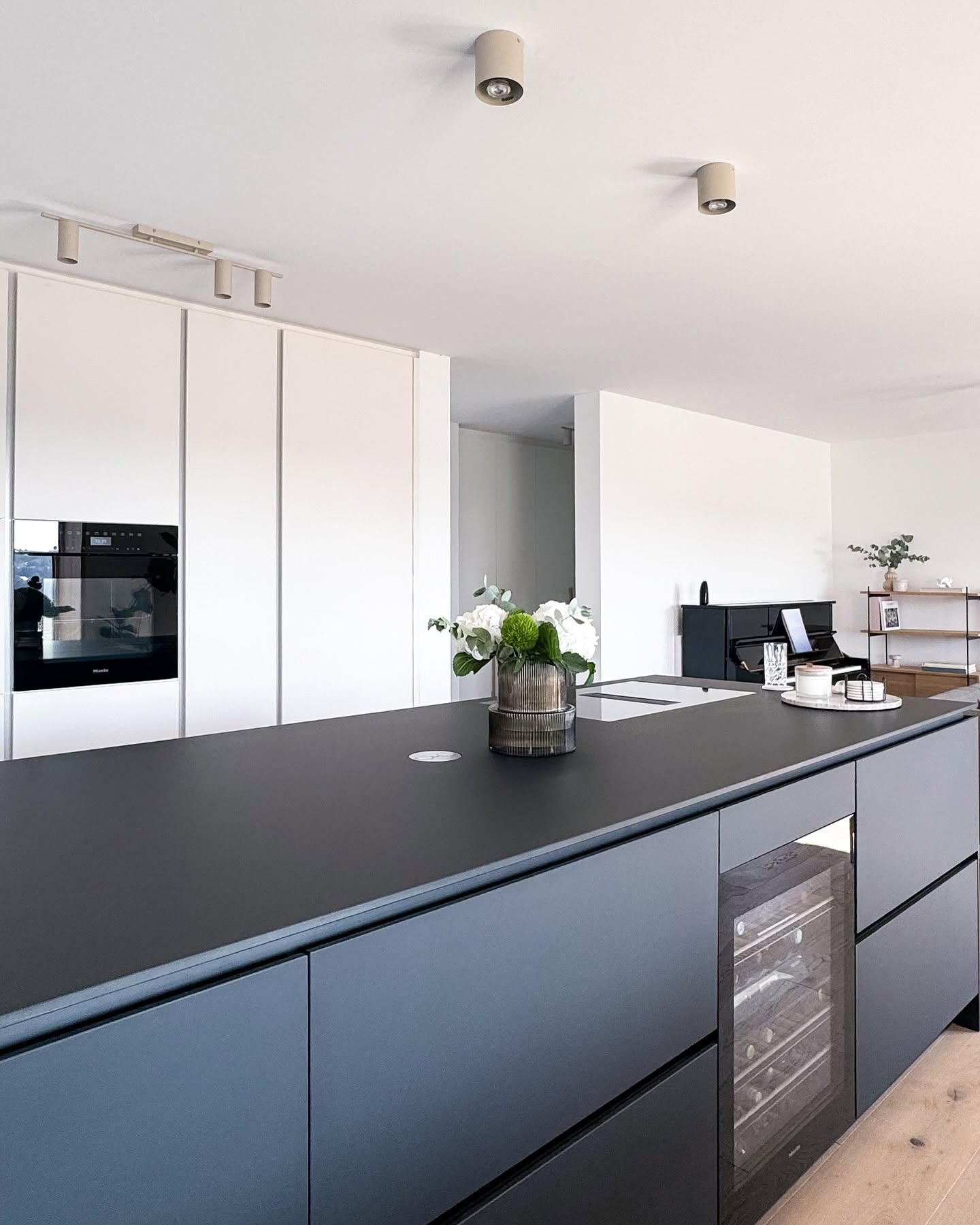 Dunkle Kücheninsel mit Weinkühlschrank und weißen Hochschränken im GERBERHAUS11A