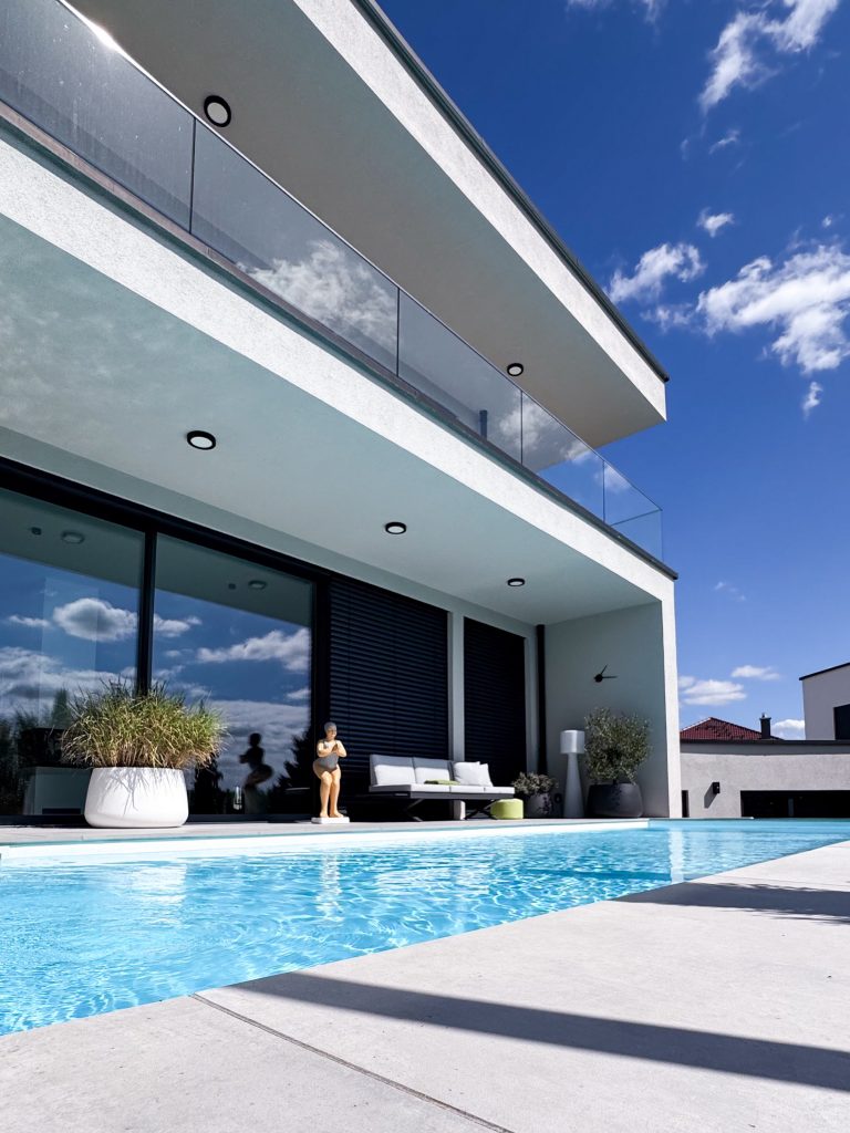 Pool vor dem GERBERHAUS12 mit überdachter Terrasse, großen Glasfronten und auskragendem Obergeschoss mit Glasbalustrade