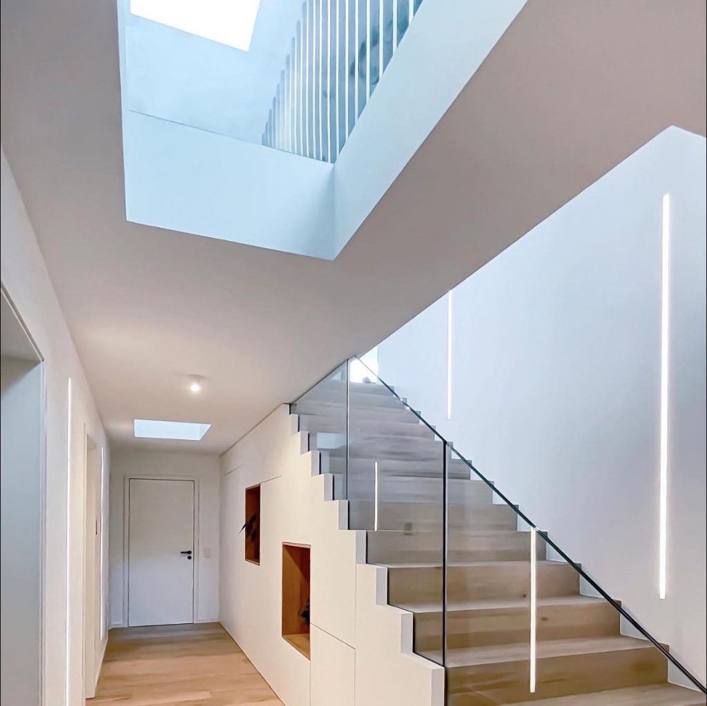 Holztreppe mit Glasgeländer und weißem Treppenschrank