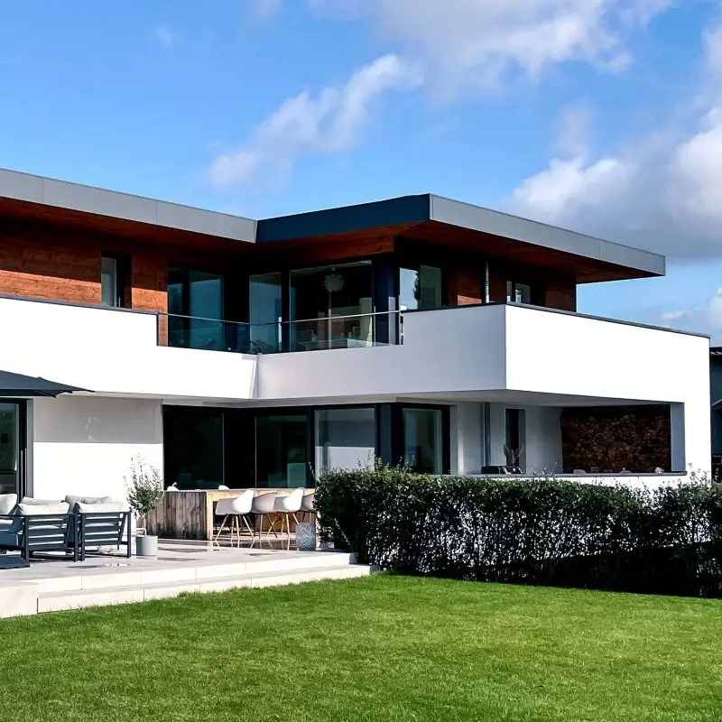 Gartenansicht #GERBERHAUS1, auch bekannt als Casa Uno, mit moderner Architektur und einem Walmdach in Flachdachoptik.