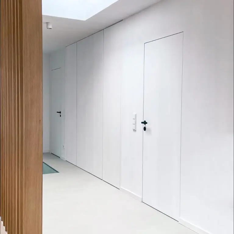 Flur im GERBERHAUS6 mit wandbündigen Türen und Einbauschränken, rechts Holzlamellen als Raumteiler.