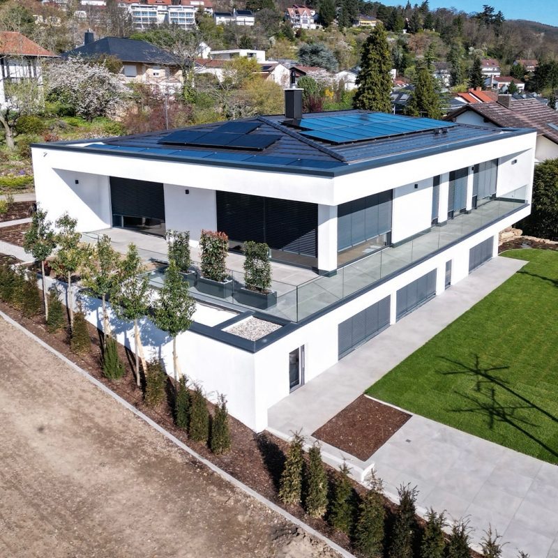 Modernes Einfamilienhaus in Hanglage mit Flachdach, Photovoltaikanlage, umlaufender Terrasse und Glasgeländer – klare Architektur von GERBER Ingenieure #GERBERHAUS16