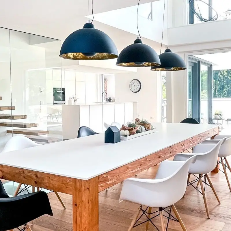 Moderner Essbereich des GERBERHAUS1 mit großem Holztisch und stilvollen Hängelampen, gestaltet von Gerber Ingenieure.