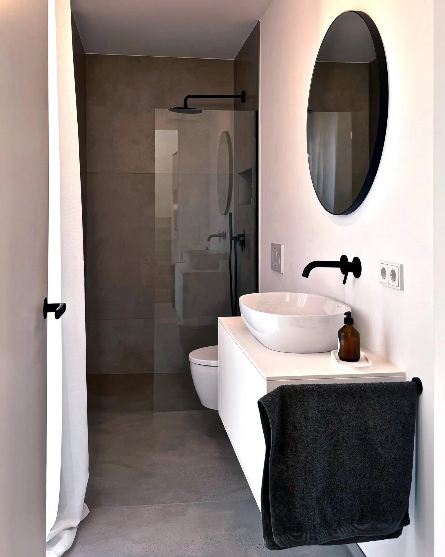 Kleines, modernes Gästebad im Gerberhaus9 mit runder Spiegel, freistehendem Waschbecken und Dusche.