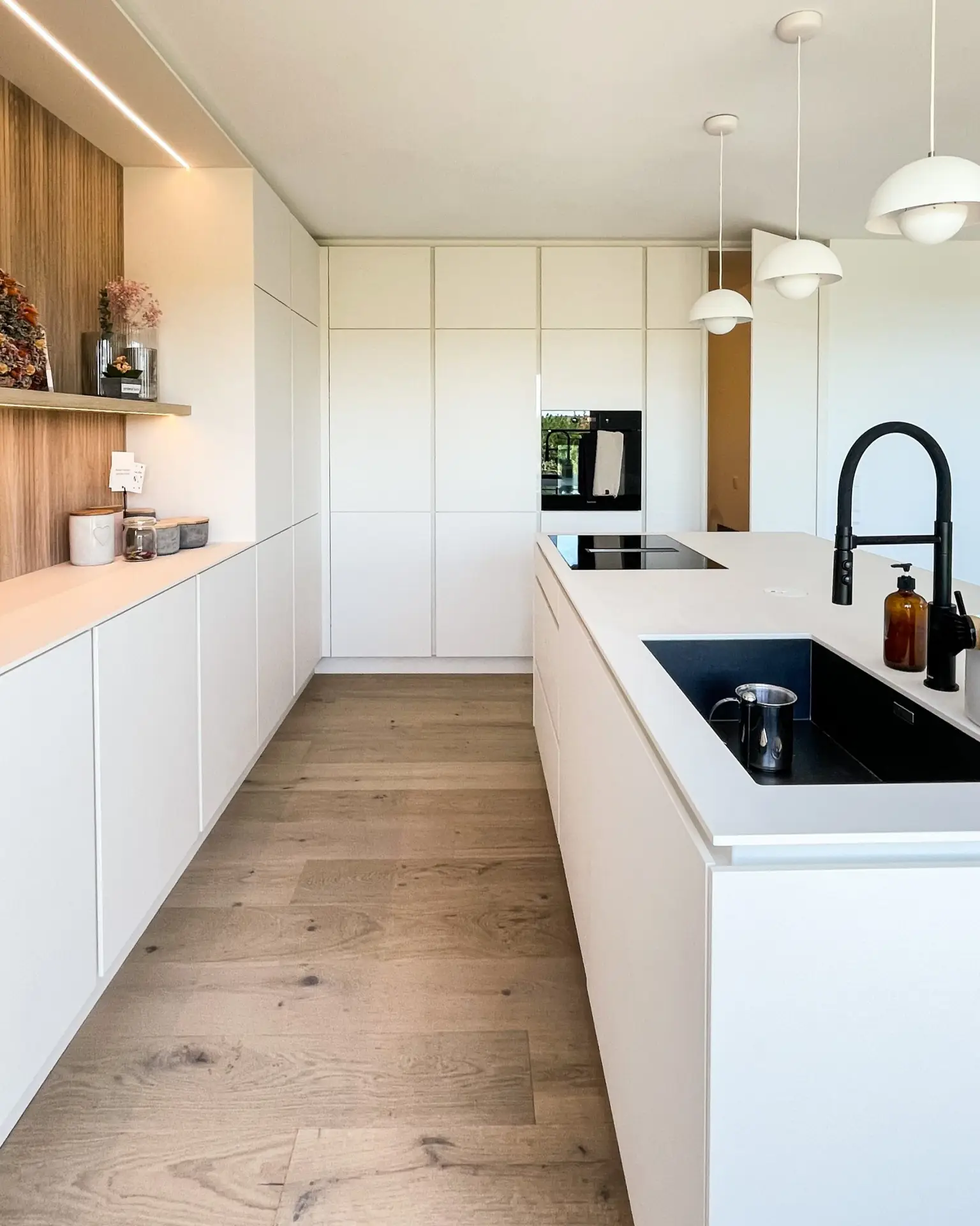 Weiße Küche im Gerberhaus9 mit großen Einbauschränken, zentraler Kochinsel und modernen Akzenten.