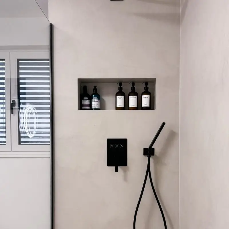 Stilvolle Dusche im Gerberhaus10B mit fugenlosem Microzement, schwarzer Regendusche, integrierter Nische und schwarzen Armaturen
