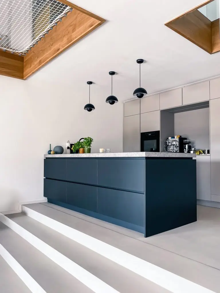 Die moderne Küche im GERBERHAUS8 besticht durch ihre Kochinsel, Pendelleuchten und eine Arbeitsplatte aus massivem Stein.