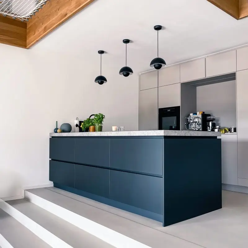 Die moderne Küche im GERBERHAUS8 besticht durch ihre Kochinsel, Pendelleuchten und eine Arbeitsplatte aus massivem Stein.