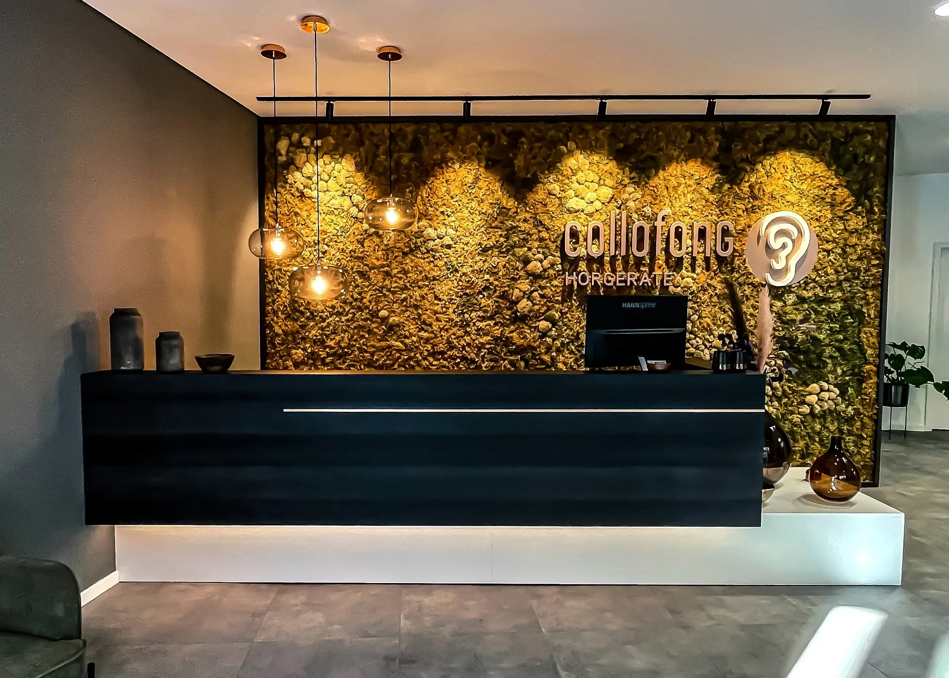 Empfangsbereich der Collofong-Filiale mit Theke und Mooswand