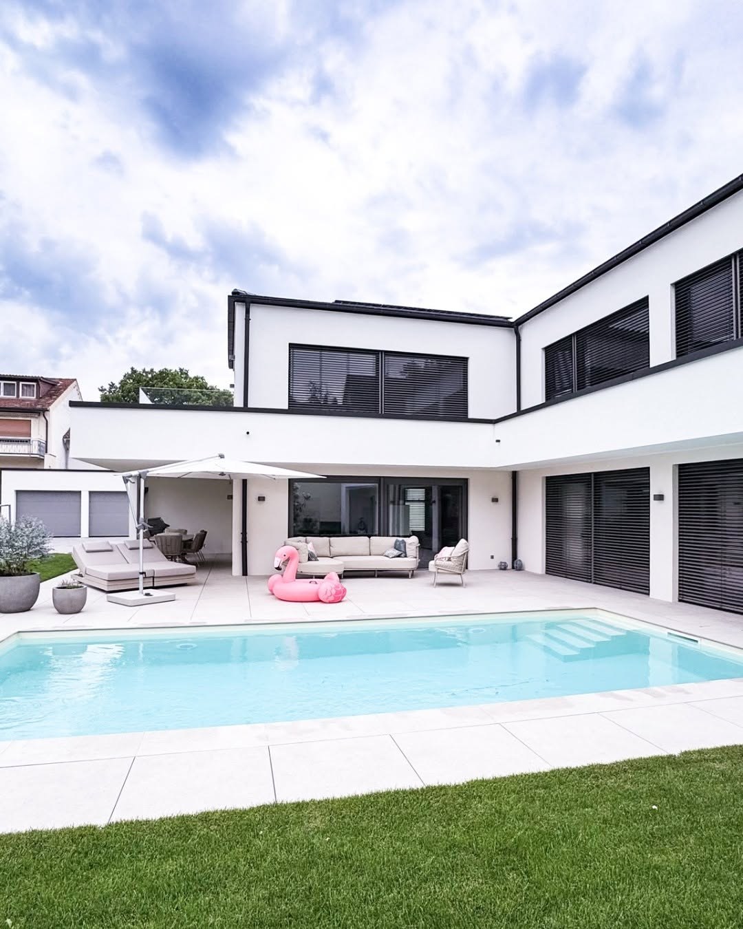 Pool mit Einstiegstreppe vor der überdachten Terrasse mit Lounge-Möbeln und Sonnenschirm am GERBERHAUS15