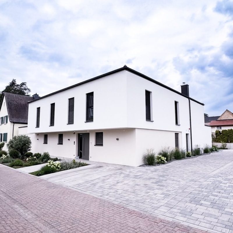 Straßenansicht des GERBERHAUS15 mit zweifarbiger Putzfassade: heller Hauptbaukörper und dunklerer Ton an der integrierten Garage