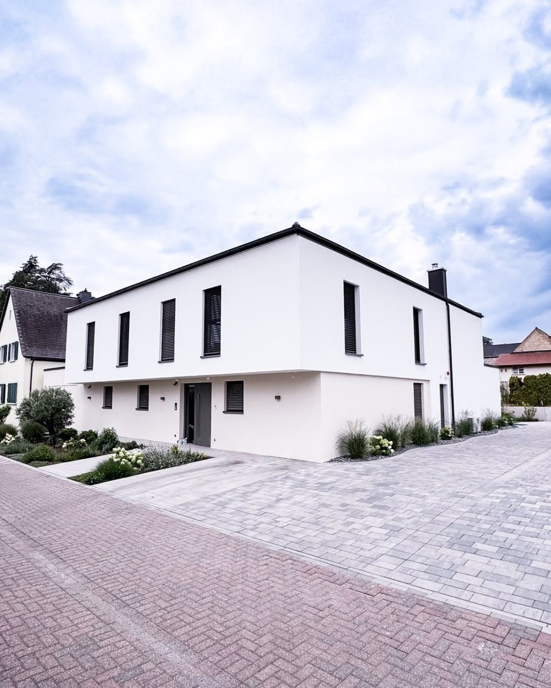 Straßenansicht des GERBERHAUS15 mit zweifarbiger Putzfassade: heller Hauptbaukörper und dunklerer Ton an der integrierten Garage