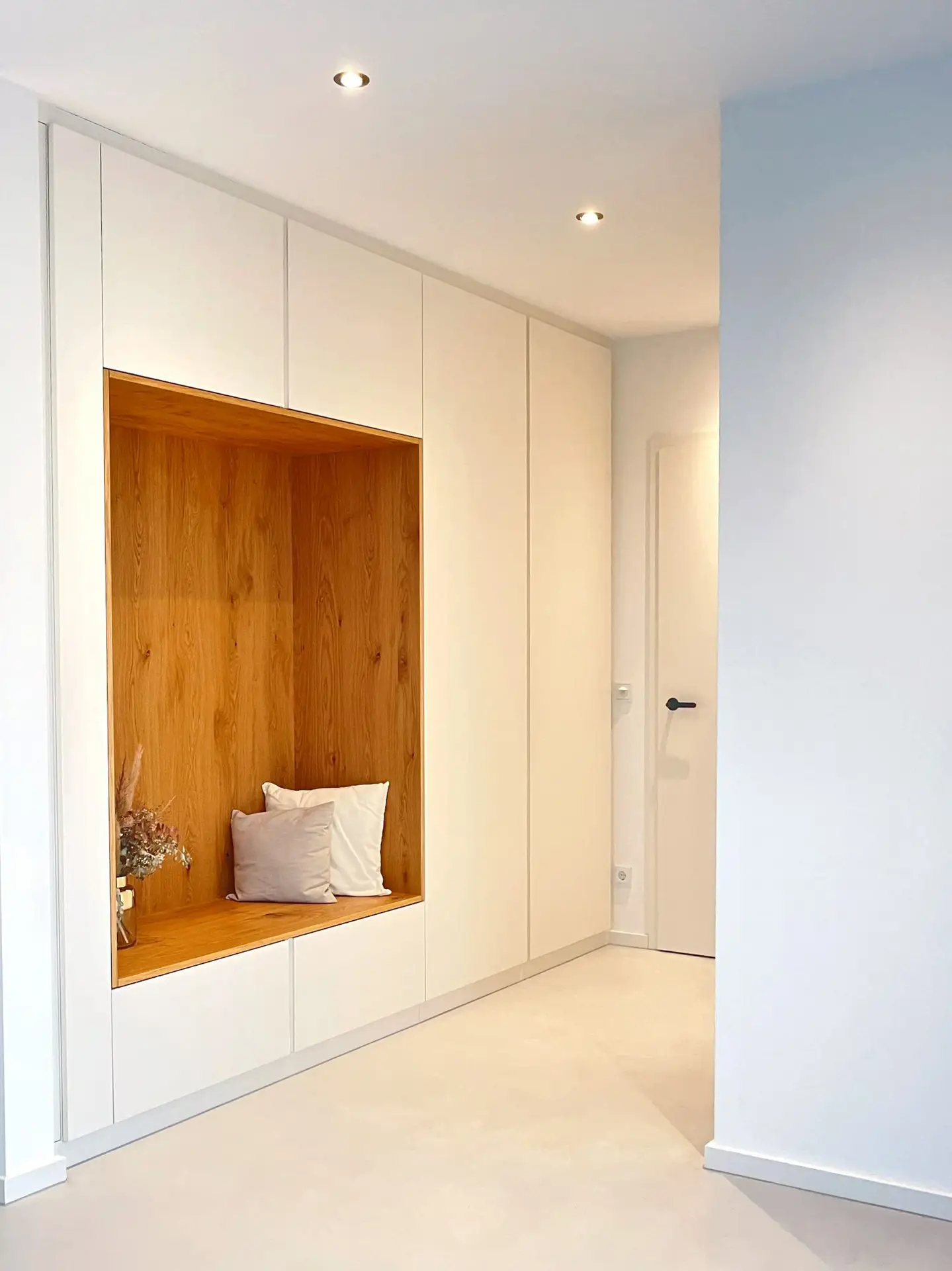 Weiße Garderobe mit holzverkleideter Sitznische
